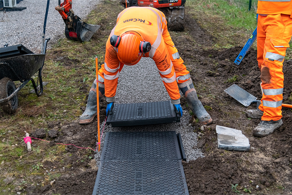 Worker laying walkway panel on prepared sub-base