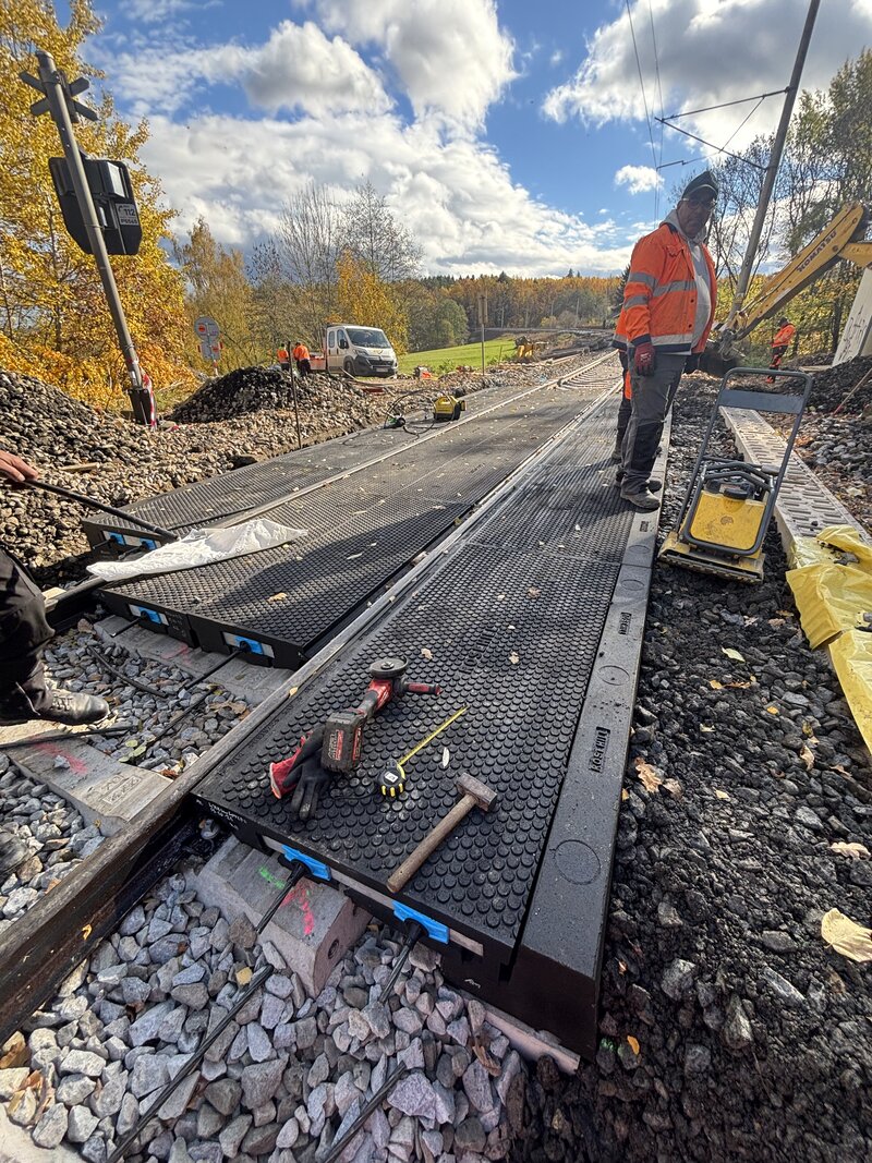 Worker inspecting completed StrandLock crossing surface with tools and signage visible